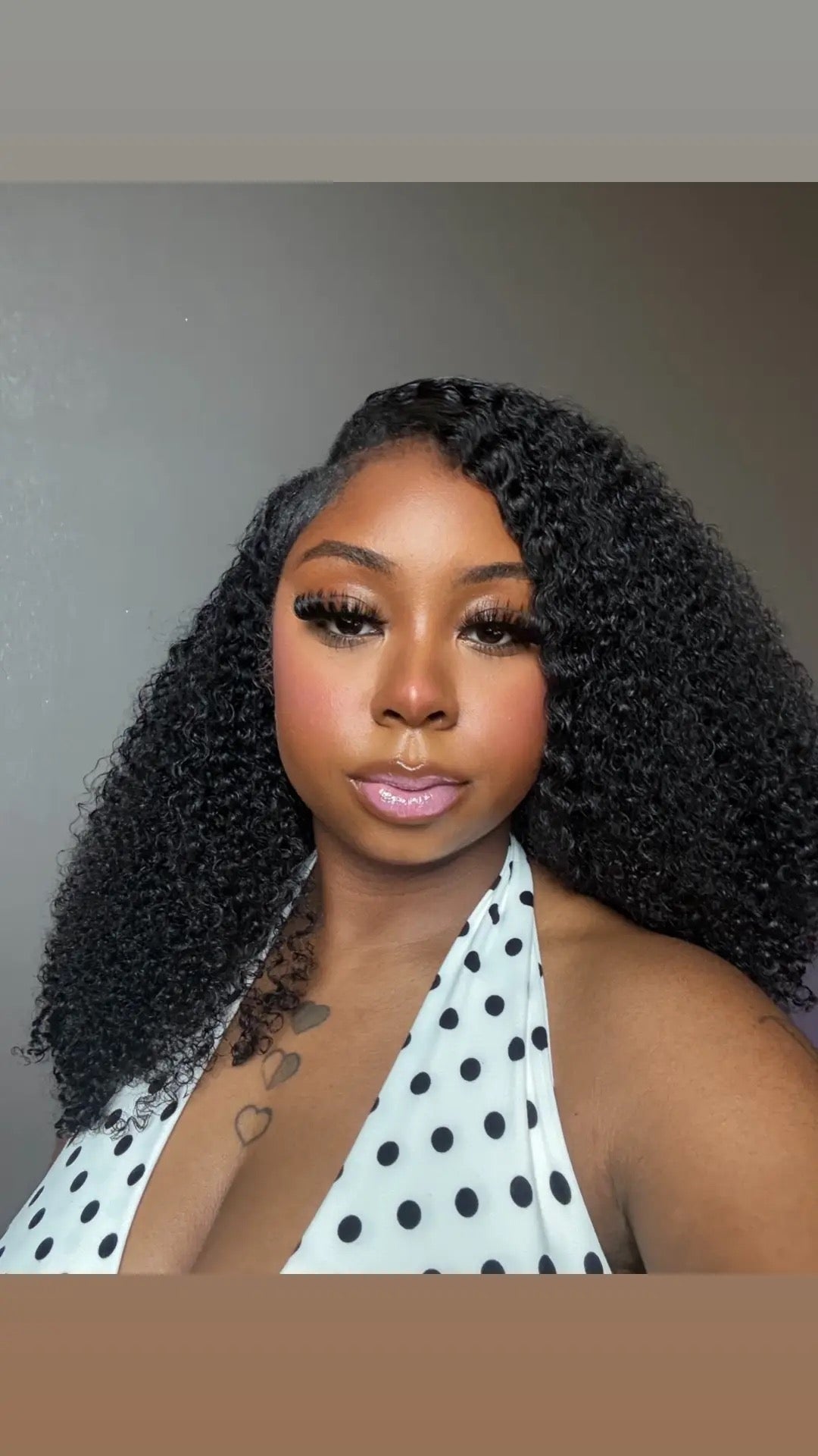 Woman with styled hair wearing a polka dot top against a neutral background