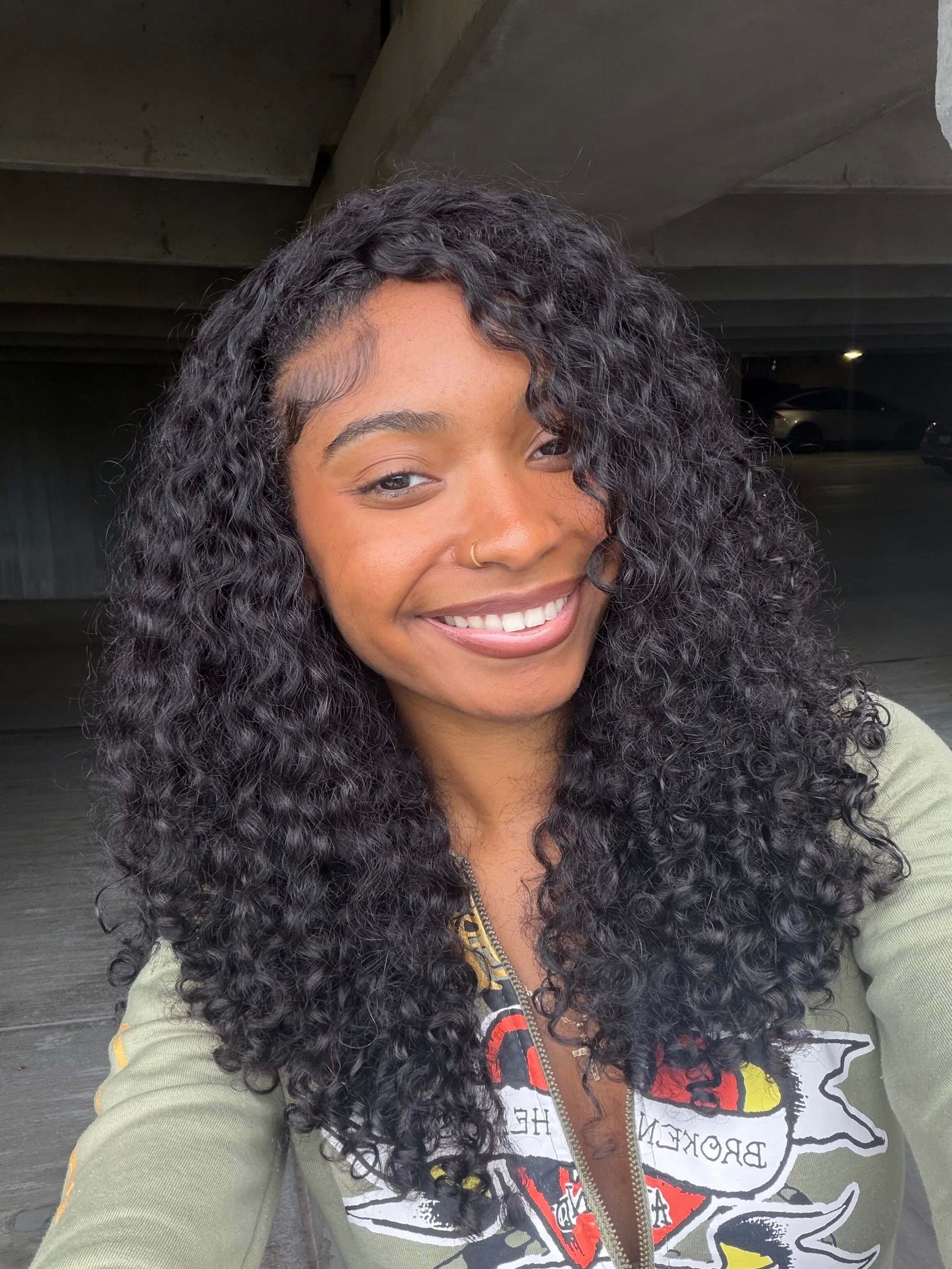 Person with burmese curly hair smiling under a bridge